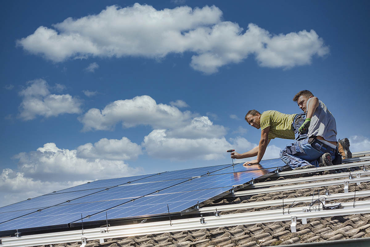 Installing solar photovoltaic panel system. Solar panel technician installing solar panels on roof. Alternative energy ecological concept.